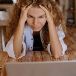 Stressed woman at home struggling with remote work on her laptop.