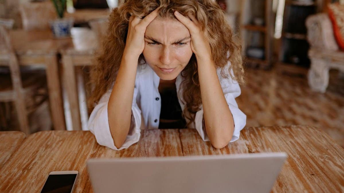 Stressed woman at home struggling with remote work on her laptop.