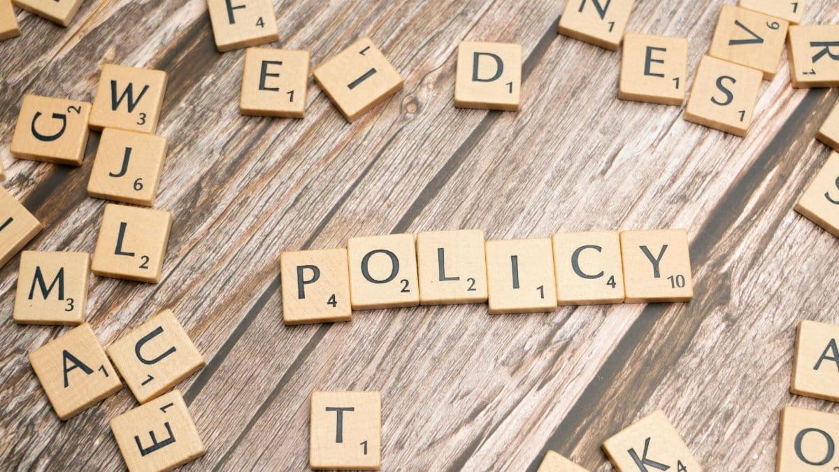 Scrabble letter tiles on a wooden background forming the word "Policy".