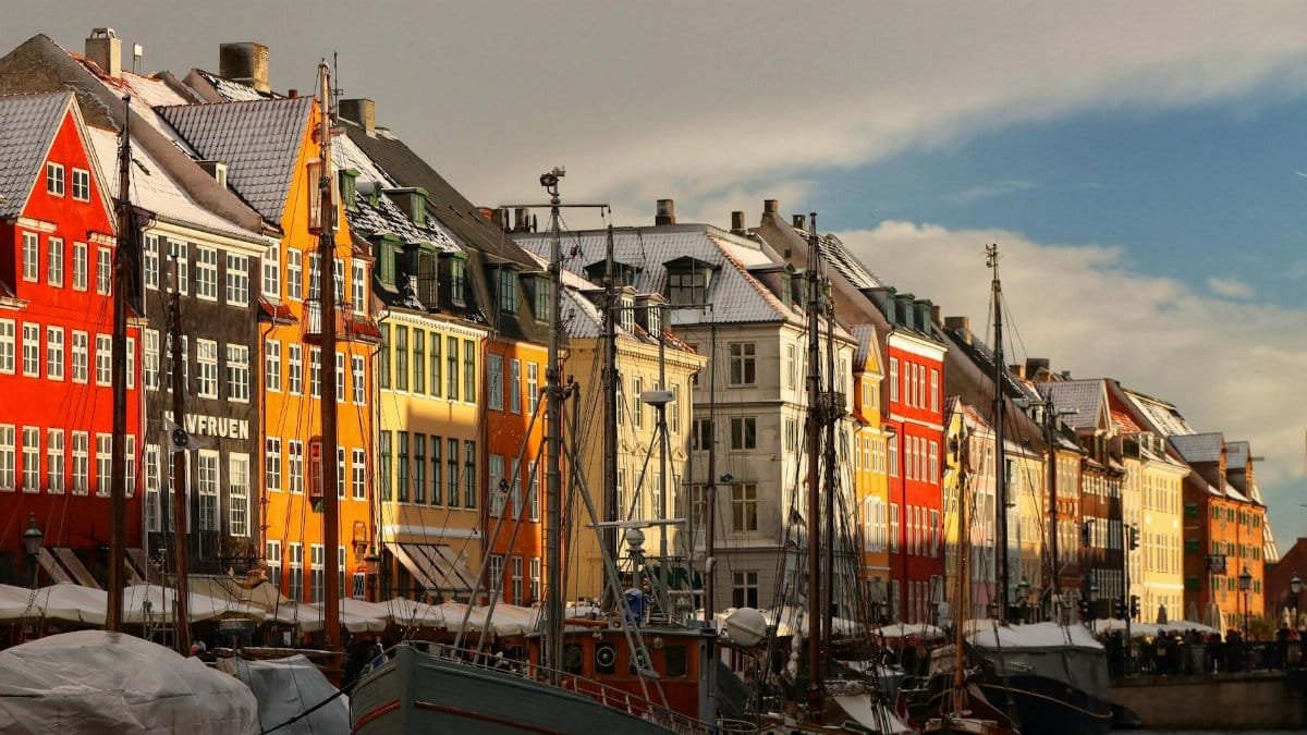 Scenic view of Nyhavn with colorful buildings and boats under winter sunlight in Copenhagen, Denmark.
