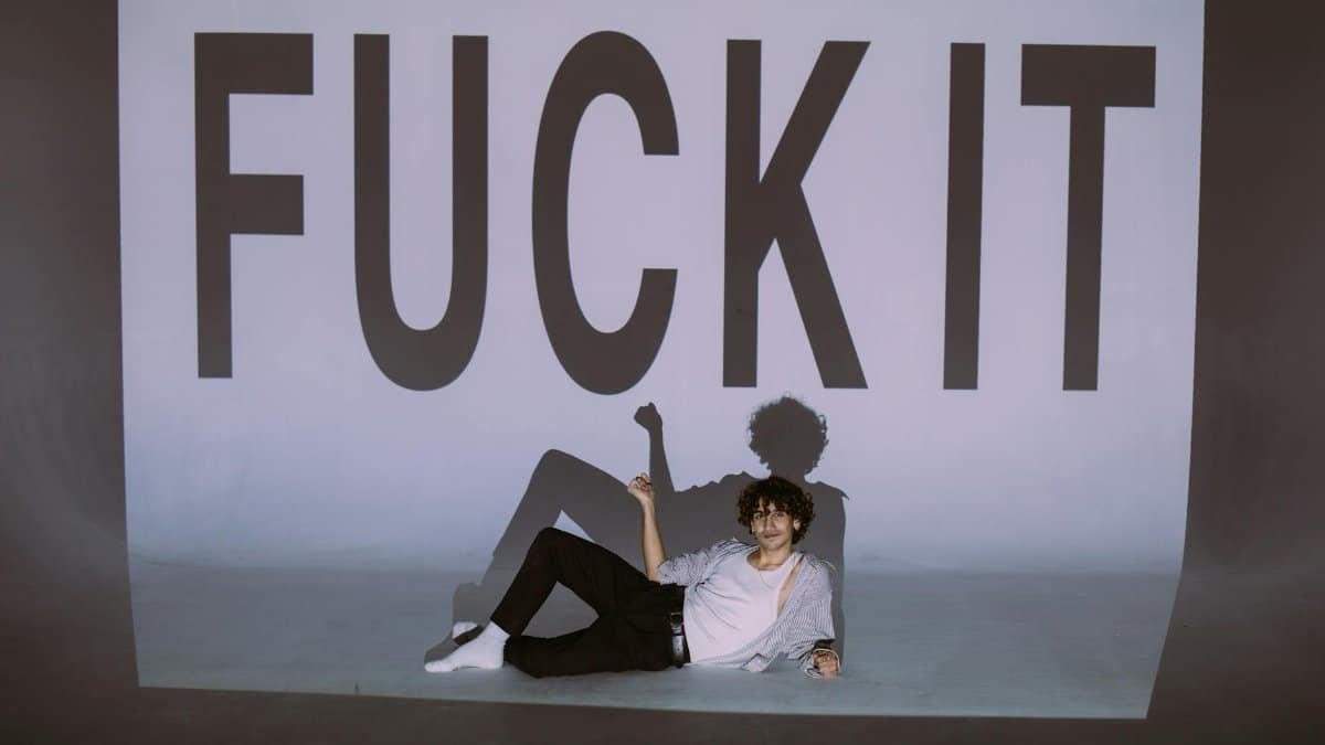 An artistic portrait of a man indoors with bold text and shadow projection.