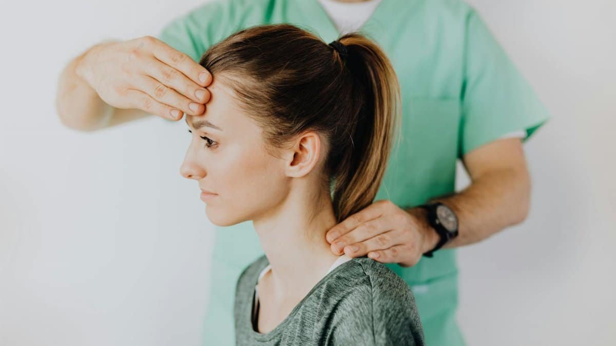 Professional massage therapist performing head and neck massage on content female patient relieving sore neck tensions
