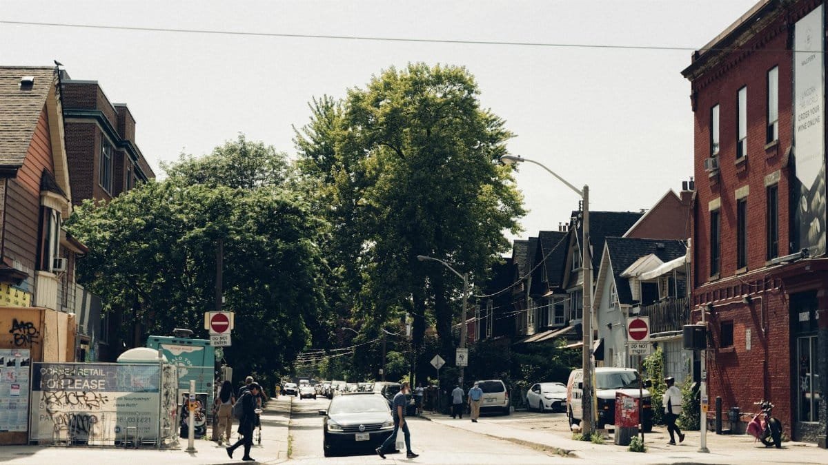 A lively urban street scene with people crossing a pedestrian lane under clear daylight.