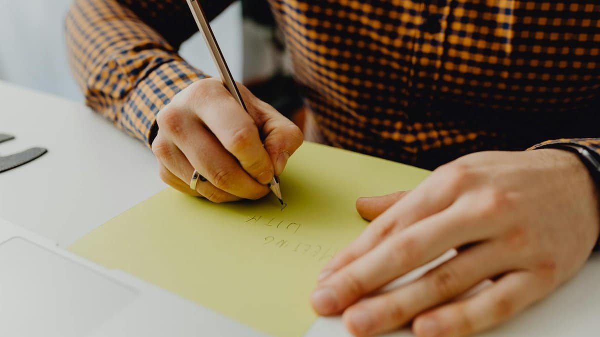 A person writing on yellow paper with a pen, capturing a moment of creativity and expression.