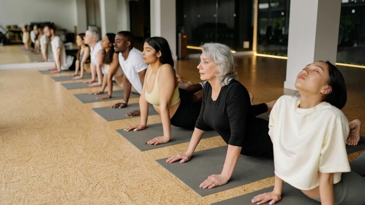 A diverse group of adults practice yoga indoors, demonstrating healthy lifestyles.