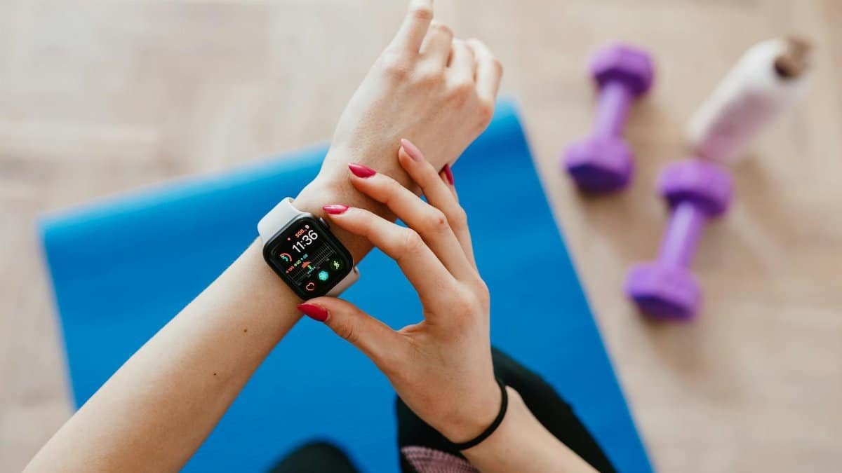 A woman checks fitness data on her smartwatch during a workout at home.