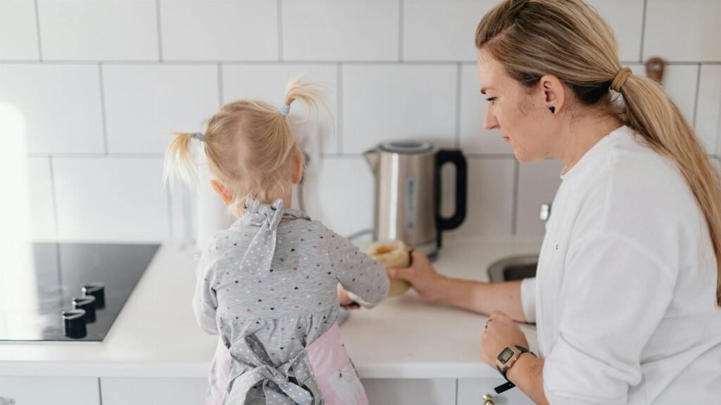 A mother helps her young daughter bake on a kitchen counter, creating a precious bonding moment.