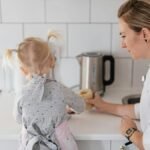 A mother helps her young daughter bake on a kitchen counter, creating a precious bonding moment.