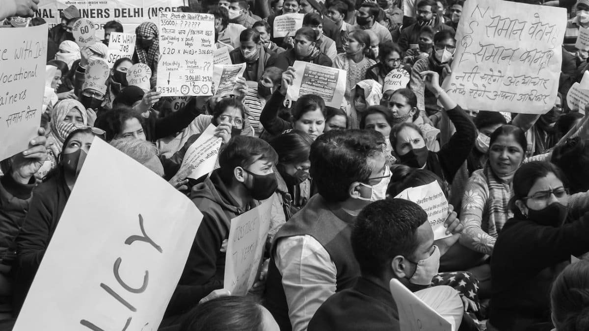 Black and white image of a crowded protest rally in Delhi advocating for policy reform.