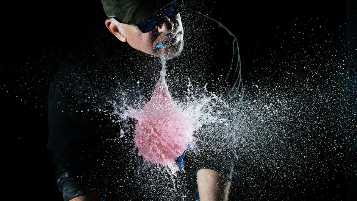 Dramatic scene of a water balloon exploding in mid-air with a person observing.