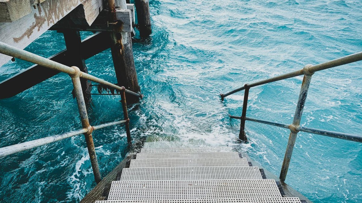 Metal stairway descending into clear turquoise ocean waters, perfect for travel inspiration.