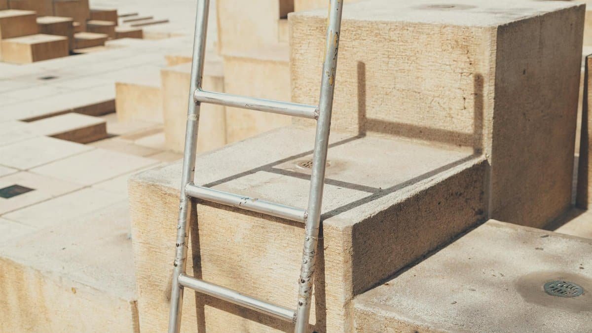 Close-up of urban blocks with a ladder casting a shadow in sunlight.