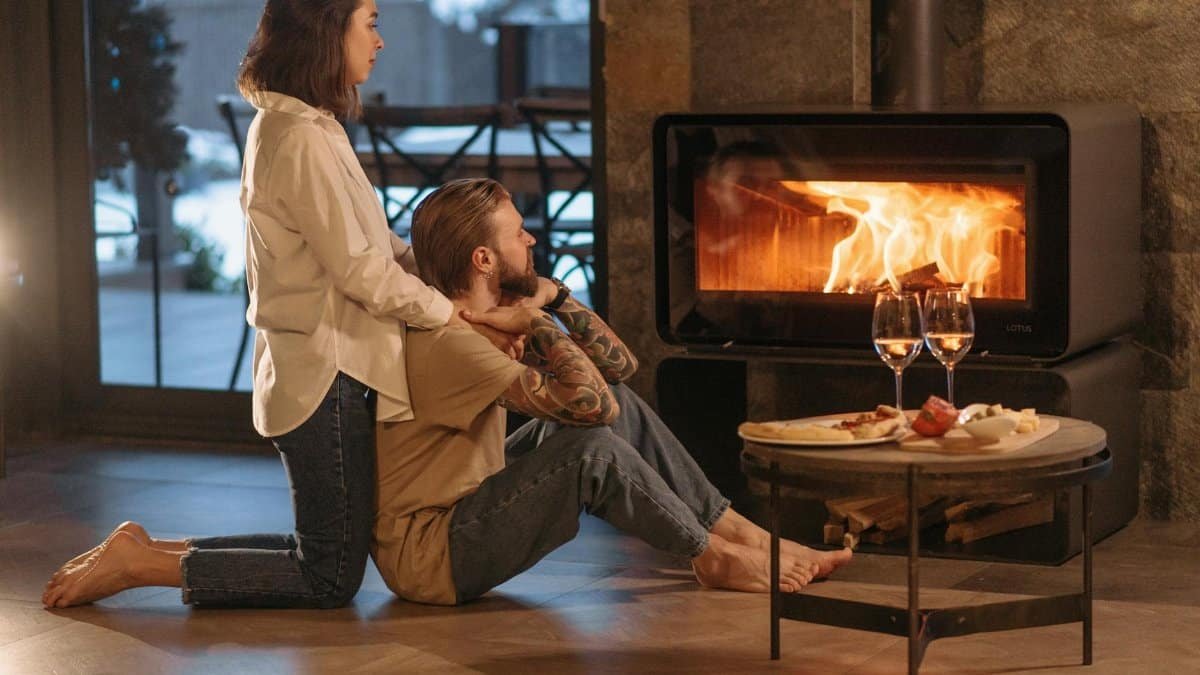 A couple relaxing by a warm fire with wine and snacks, creating a cozy winter mood.