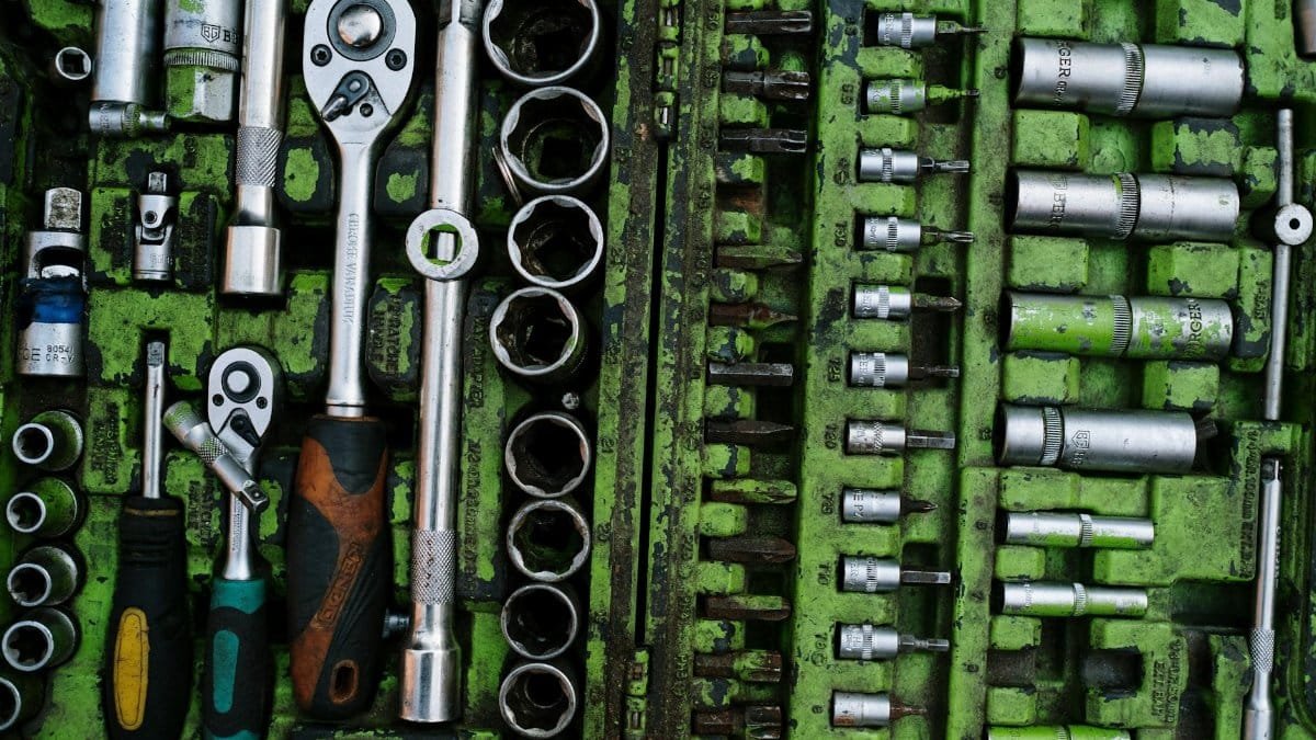 A well-organized set of metal tools in a green toolbox with ratchets and screwdrivers.
