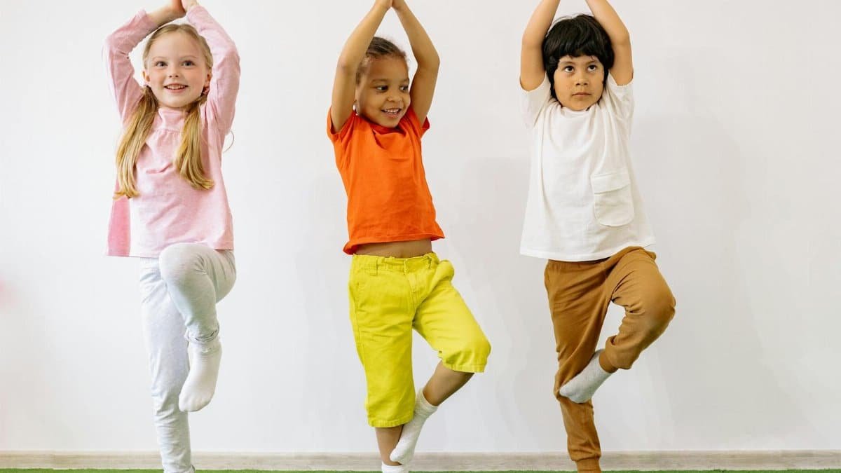 Three diverse children practicing yoga indoors, showcasing joy and balance.