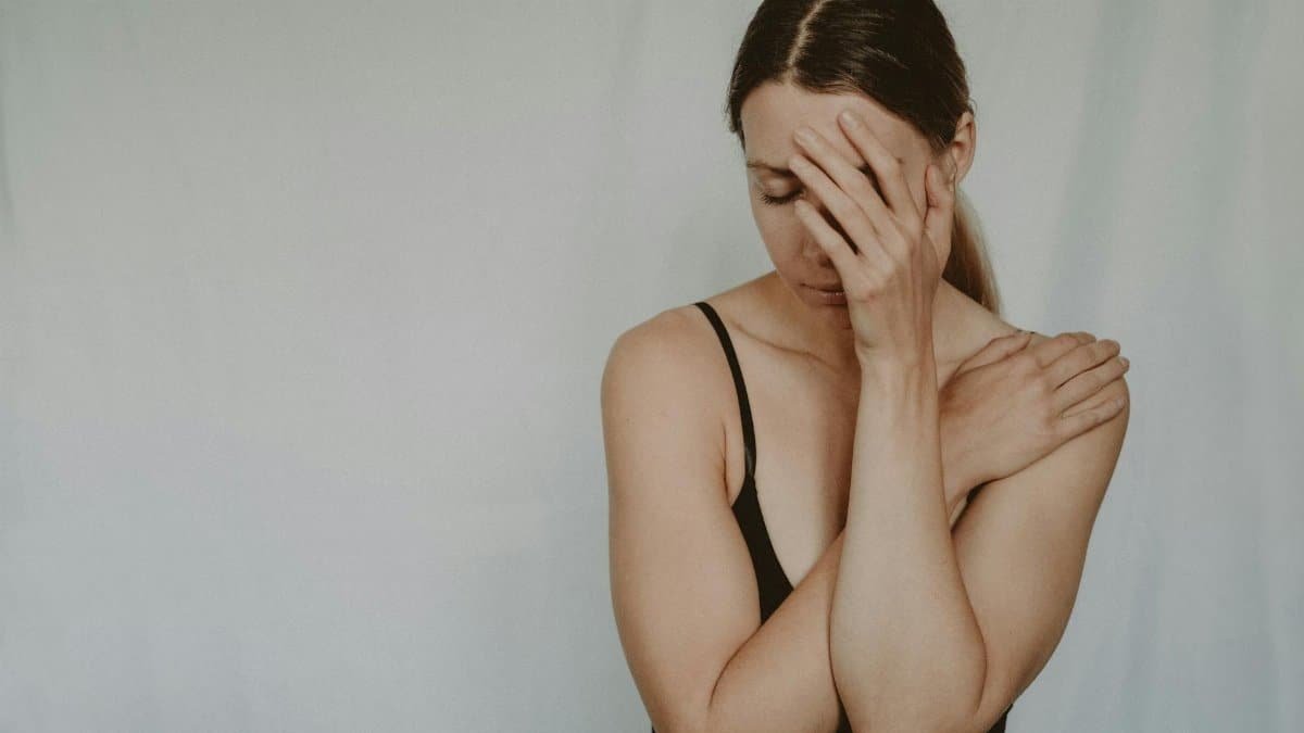 A woman in contemplation with a hand on her face, expressing emotional distress.