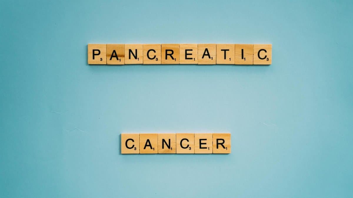 Wooden tiles spelling pancreatic cancer on blue. Health awareness concept.