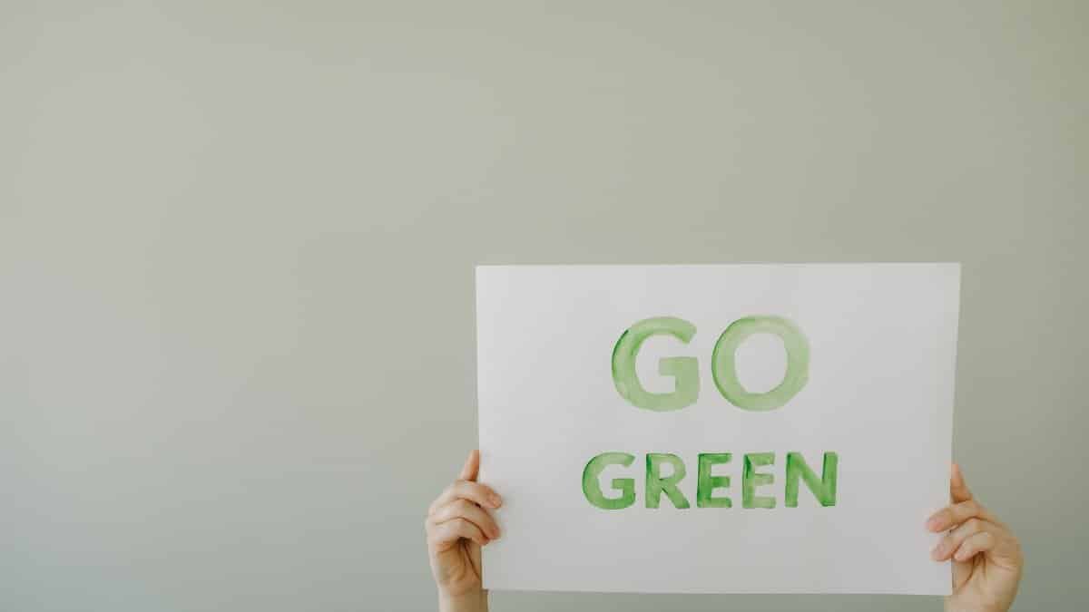 Image of hands holding a 'Go Green' sign to promote environmental awareness and sustainability.