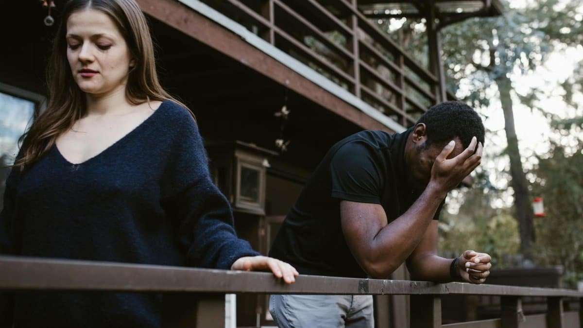 A couple experiencing a breakup on a wooden deck, expressing sadness and separation.