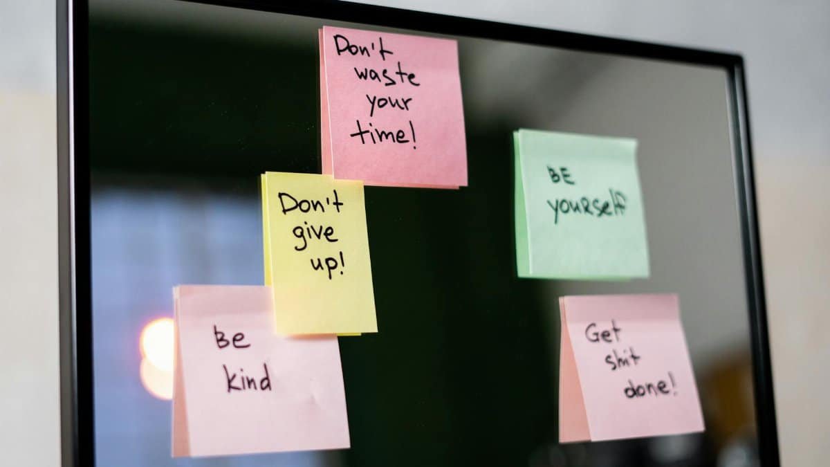 Colorful sticky notes with motivational messages on a mirror reflecting positivity.