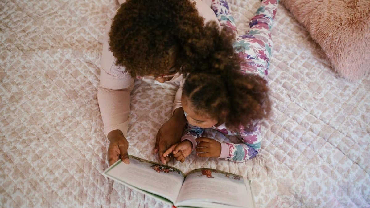 A mother and daughter enjoying storytime on a cozy bed, fostering bonding and togetherness.
