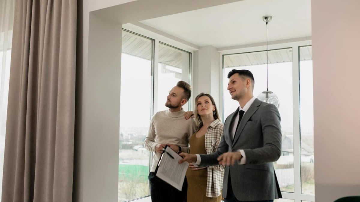 A real estate agent showing a modern home to a young couple during a daytime viewing.