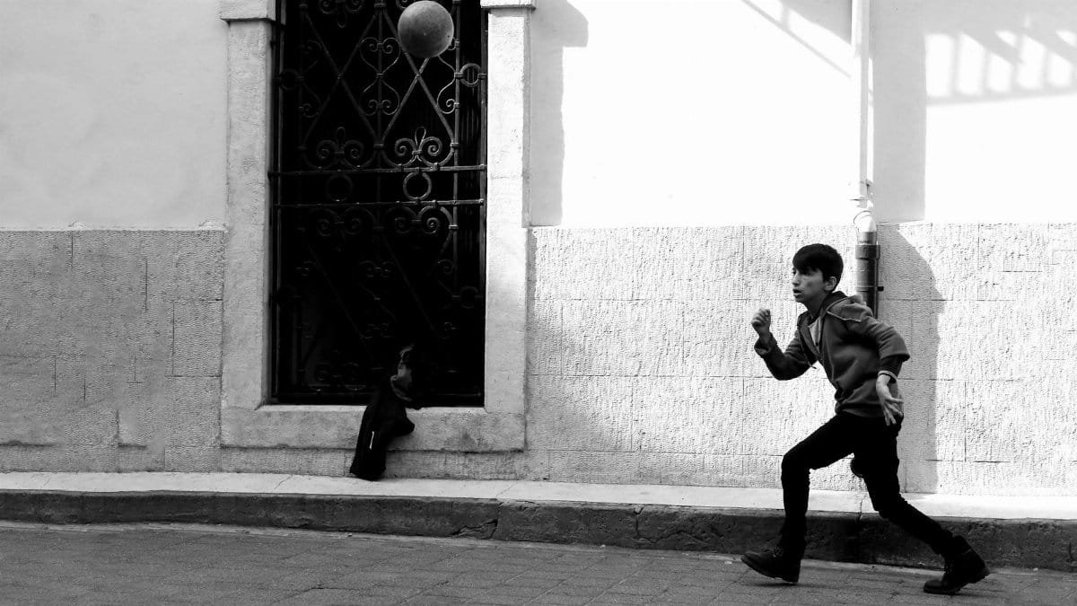 A child runs across a city street, capturing motion and urban life in black and white.