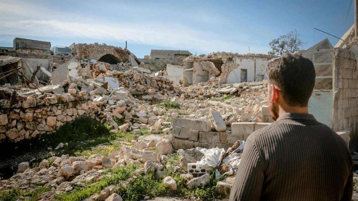 A man looks at the rubble of desolated buildings in Idlib, showcasing the impact of conflict.