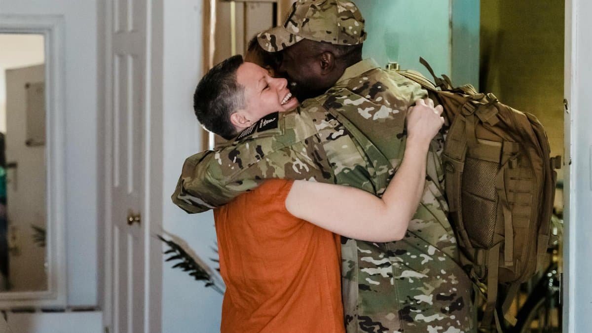A loving embrace between an interracial couple celebrating a heartfelt homecoming.