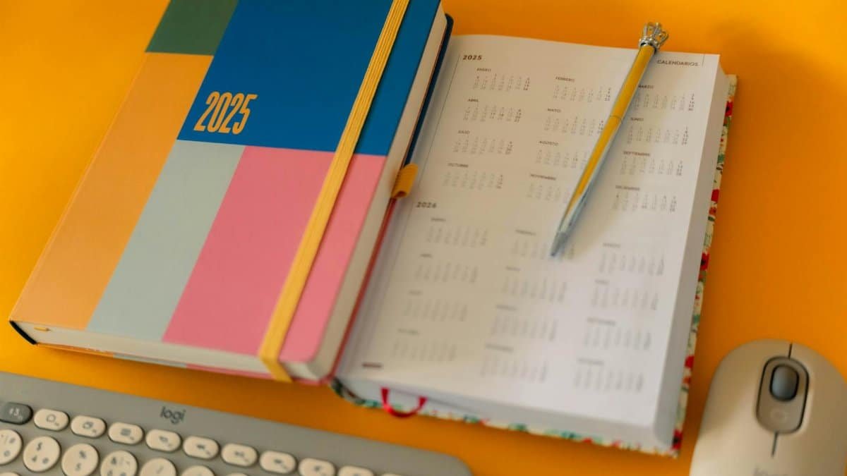 Colorful 2025 planner and calendar with pen on a bright yellow desk.