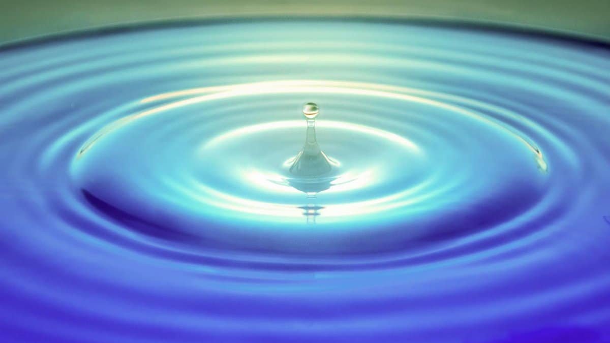 Captivating macro photography of a water droplet forming ripples, showcasing purity and motion.