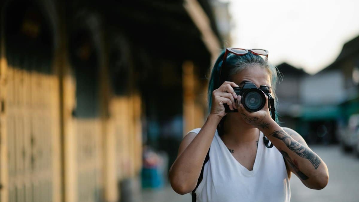 Female photographer capturing shots in an urban setting with a blurred background.