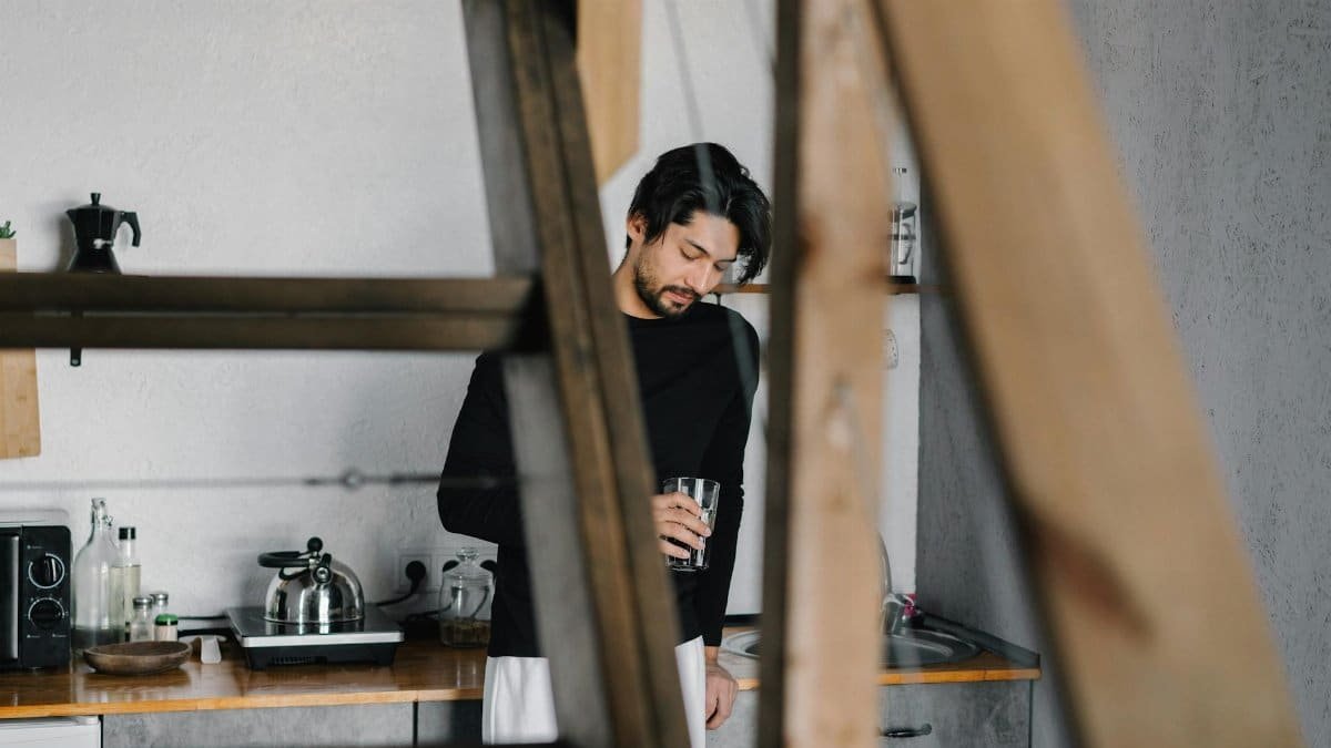Capture of a man holding a drink in a stylish kitchen, exuding relaxation.