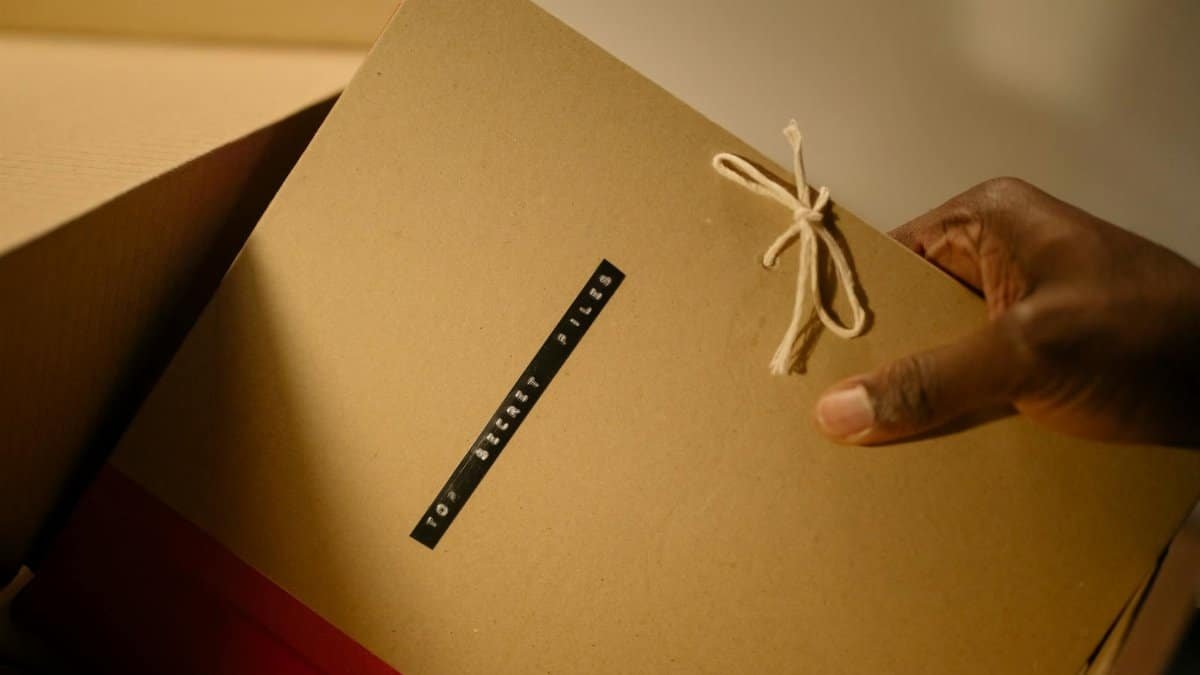 Close-up of hand holding top secret document folder in a box.