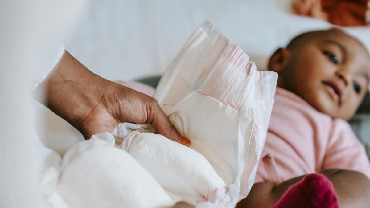 A mother gently changes her baby's diaper in a calm, cozy home setting.