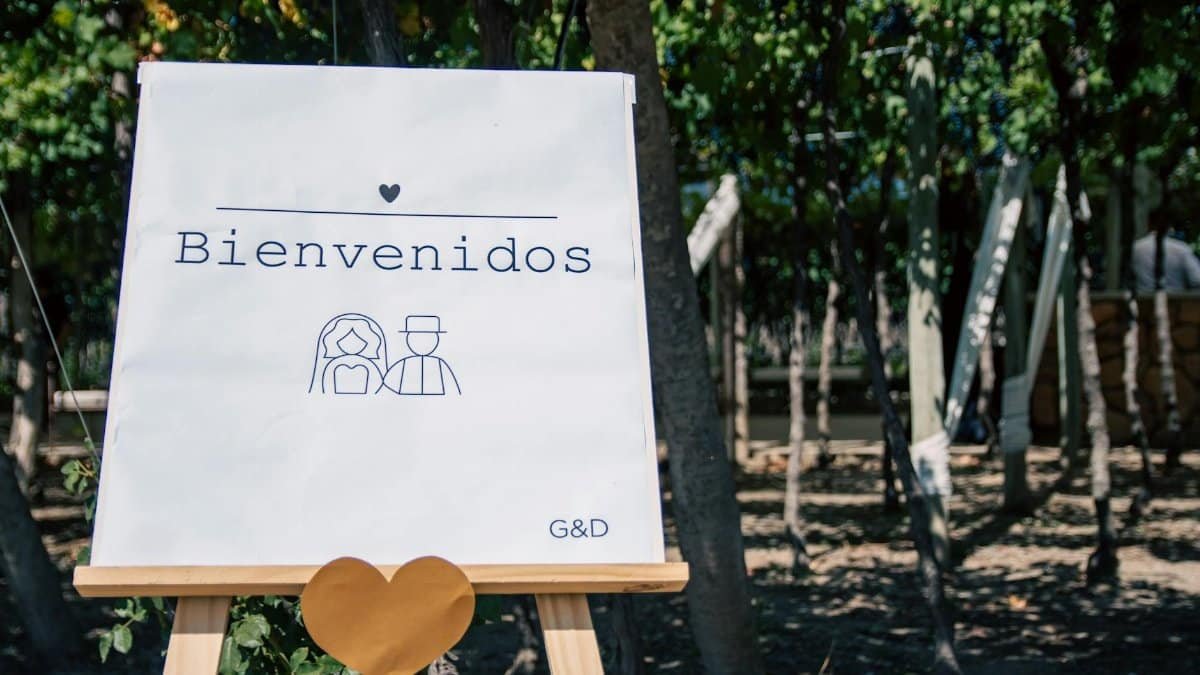 Welcome sign for outdoor wedding with trees and heart decor.