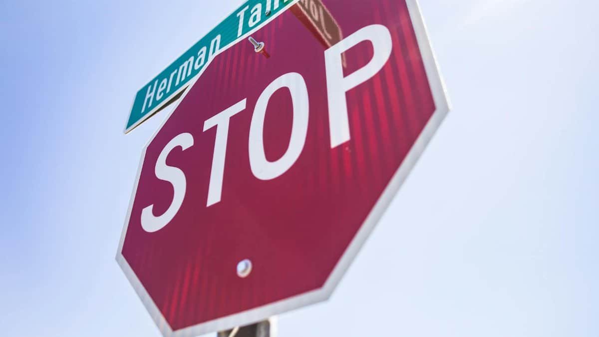 Red stop sign with street name visible against clear blue sky.