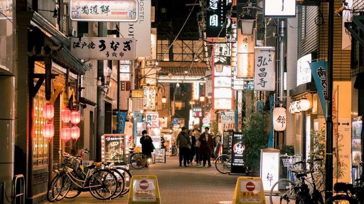 Bustling evening scene of Osaka's vibrant shopping street with illuminated signs and people walking.