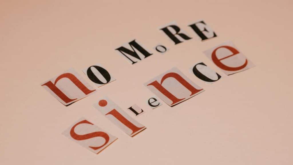 Typography artwork using cutout letters spells 'No More Silence' against a beige background.