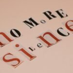 Typography artwork using cutout letters spells 'No More Silence' against a beige background.