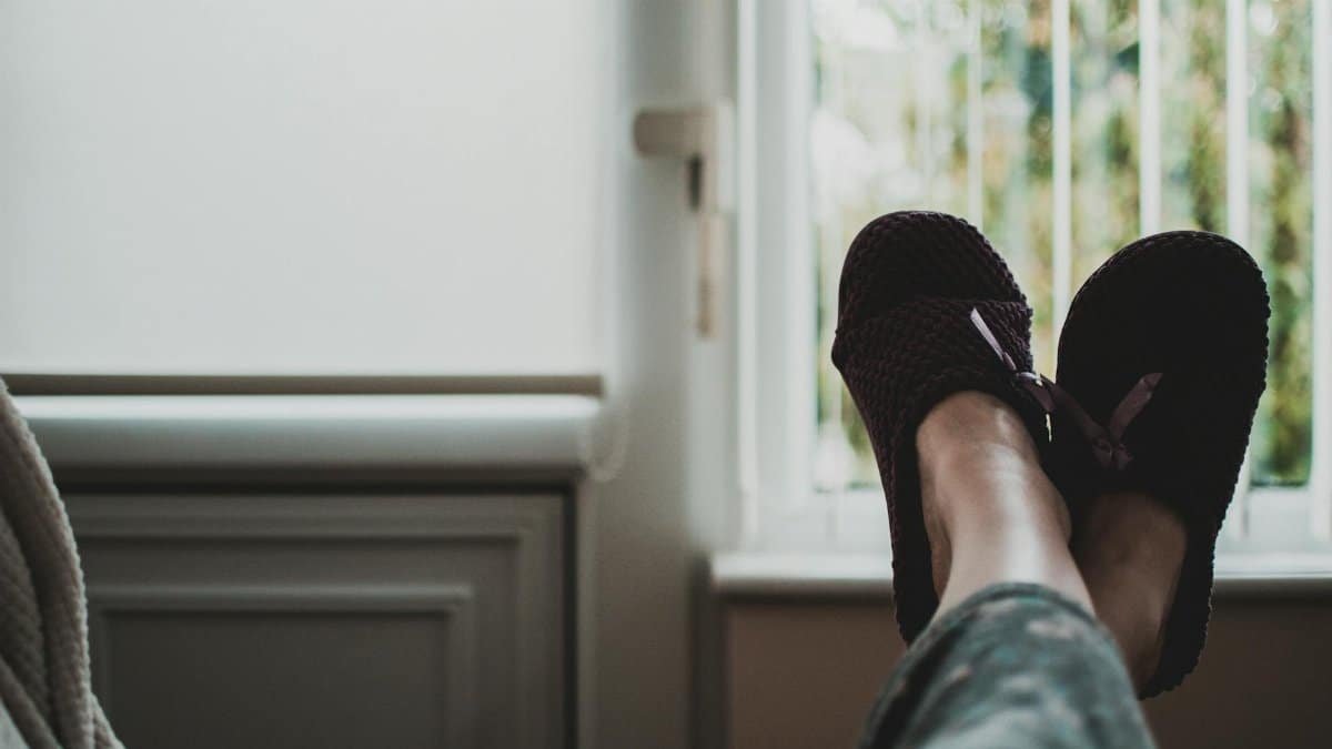 A cozy, relaxed atmosphere with feet in slippers up by a window, perfect for leisure and tranquility.