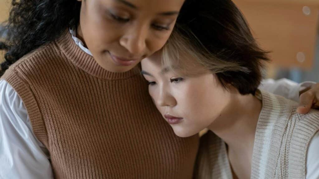 A tender moment of support between two women indoors, conveying care.