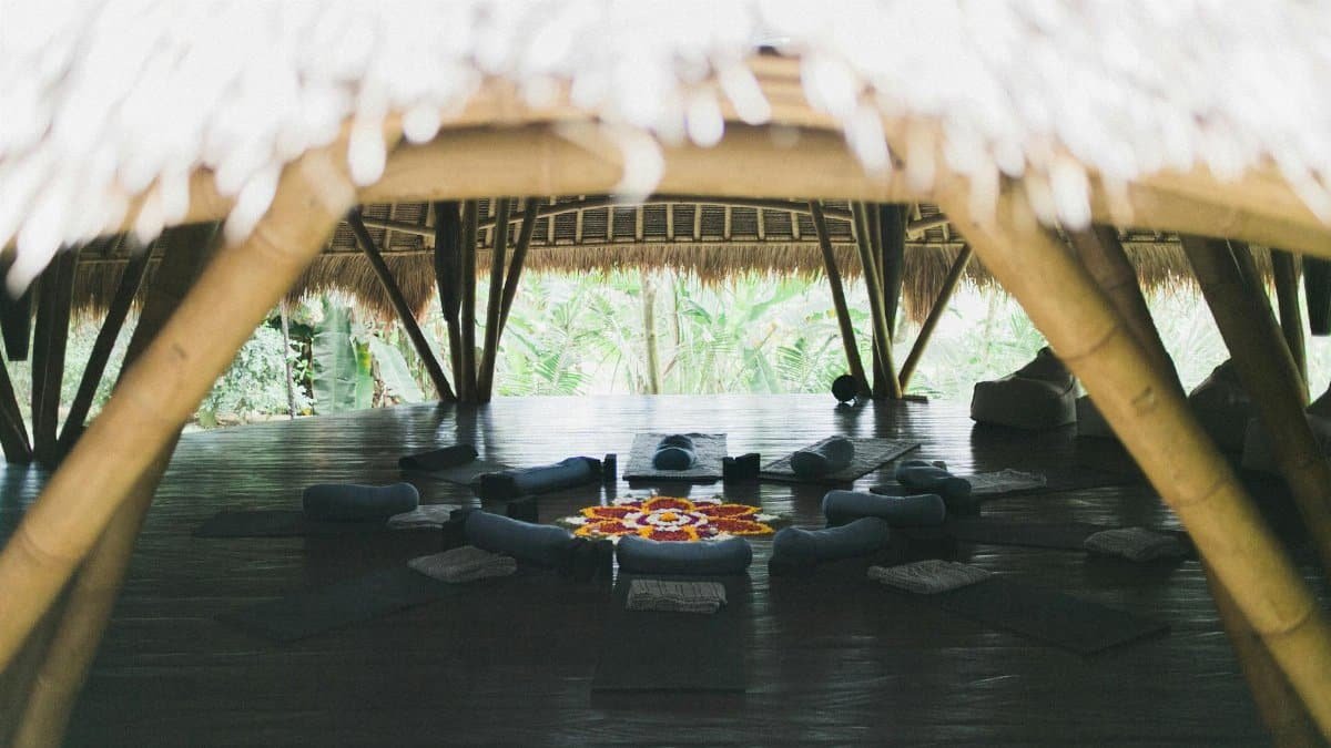 A tranquil tropical gazebo featuring yoga mats and pillows, perfect for meditation.
