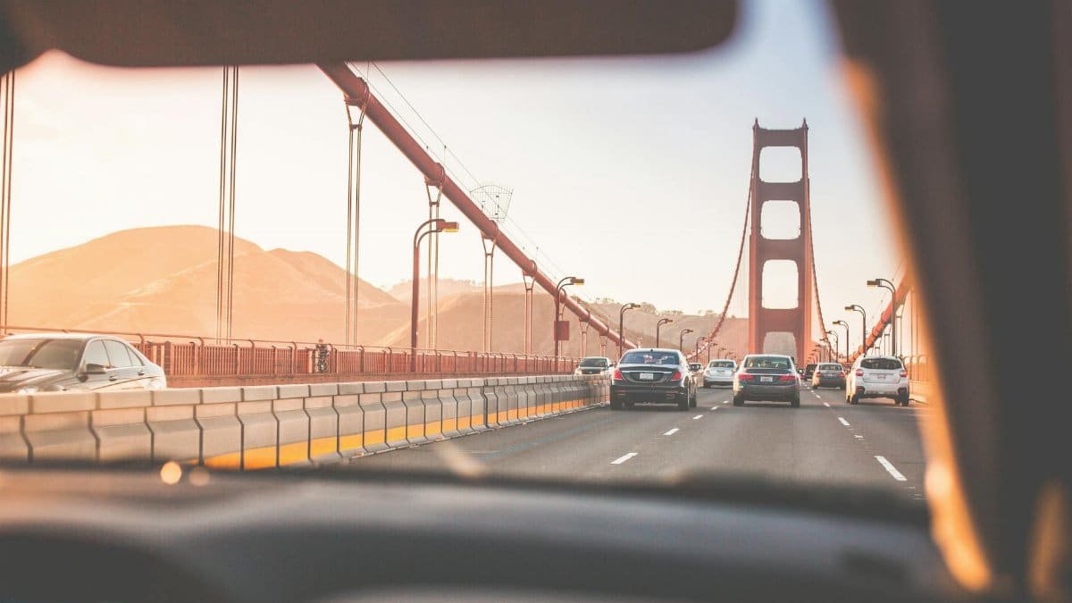 A scenic drive across San Francisco's iconic Golden Gate Bridge during sunset, capturing vehicles on the road.