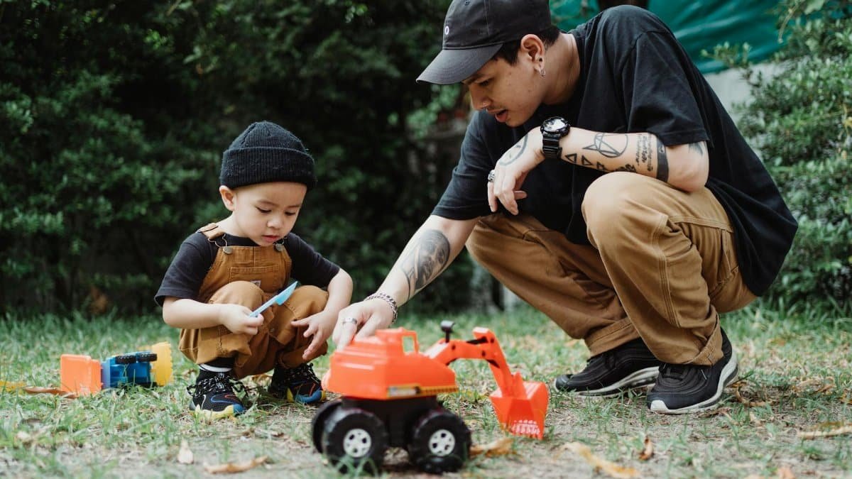 Father and son enjoying quality time outdoors playing with a toy excavator, emphasizing family bonding and childhood fun.