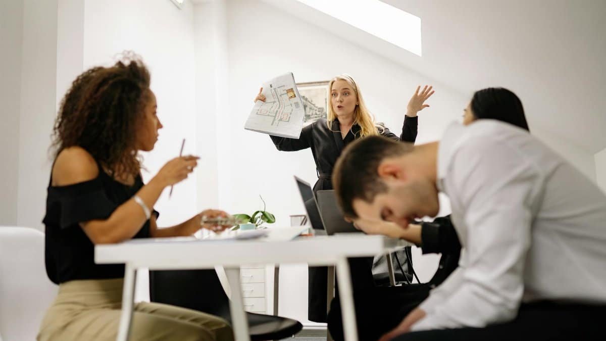 Team experiencing stress during a heated office meeting. Diverse colleagues engage in emotional discussion indoors.
