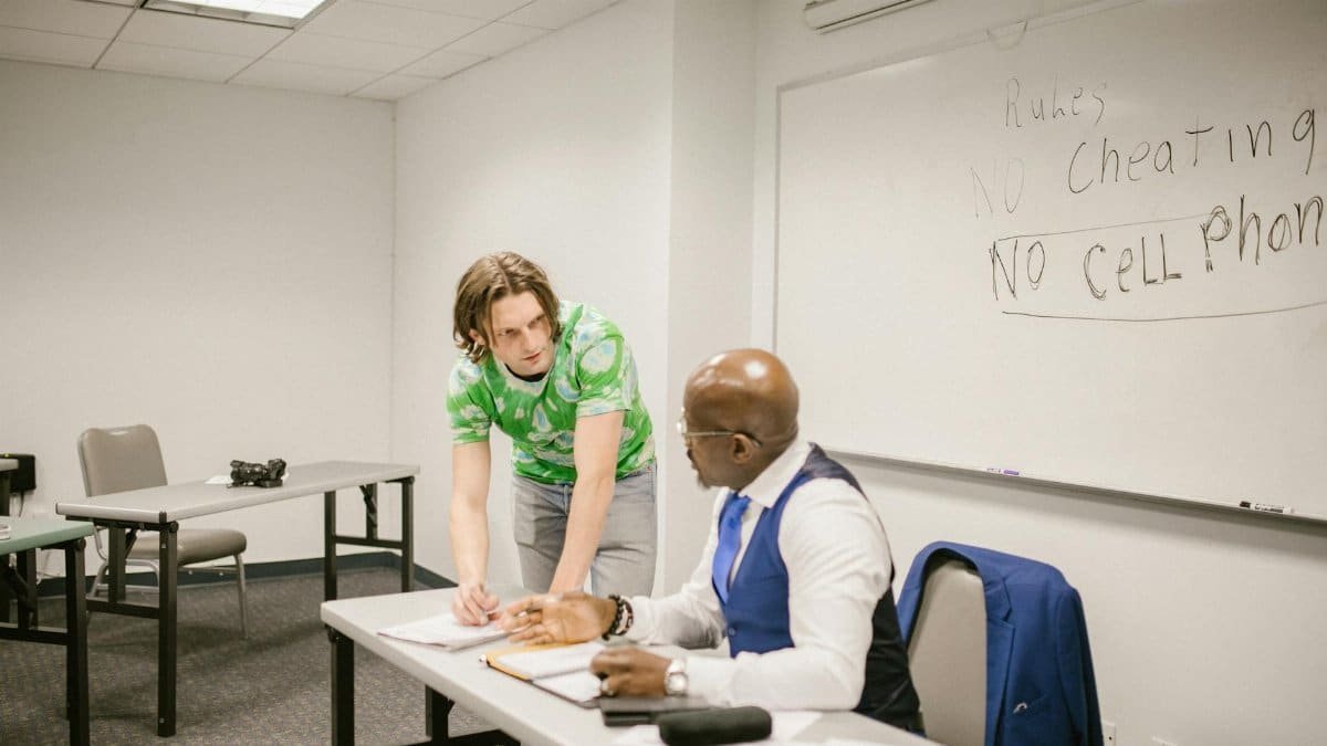 A teacher and student discuss exam rules in a modern classroom setting.