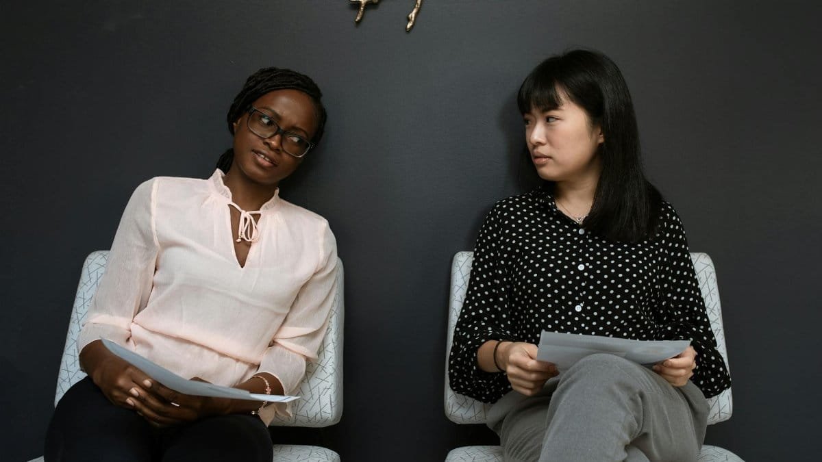 Two businesswomen having a discussion in a sleek, modern office setting.