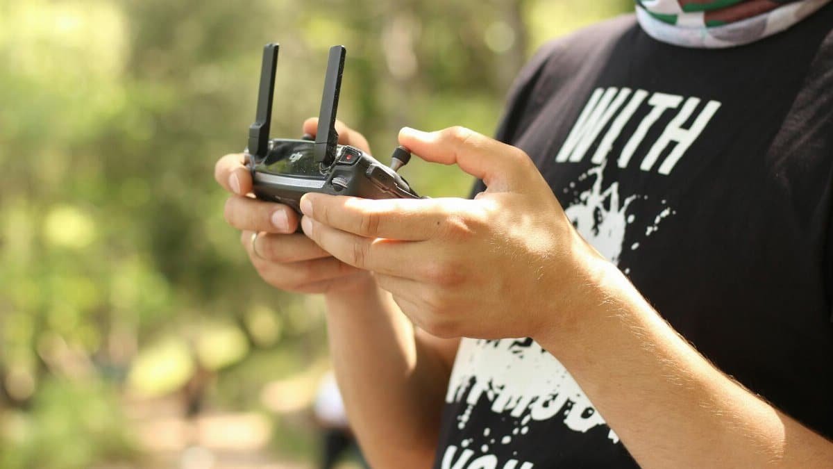 A person holding a wireless game controller in a sunny outdoor setting. Leisure and tech concept.