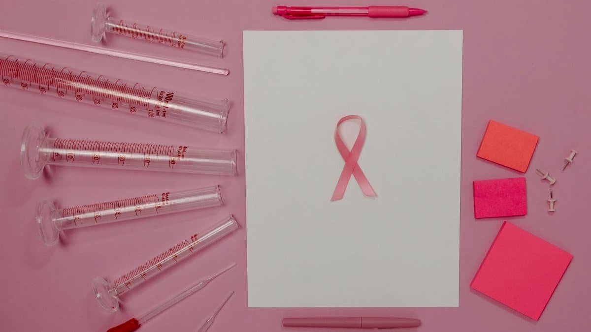 Pink ribbon and lab equipment symbolize breast cancer awareness and research.